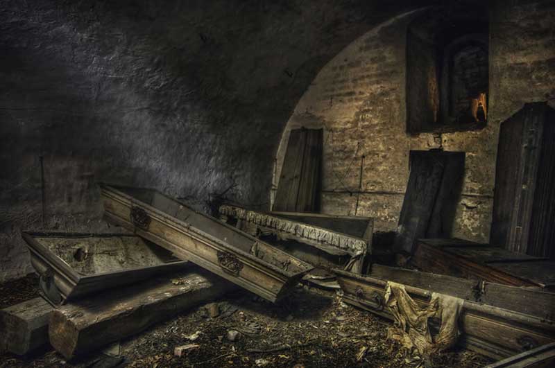The black figure in an old abandoned crypt full of mostly empty coffins